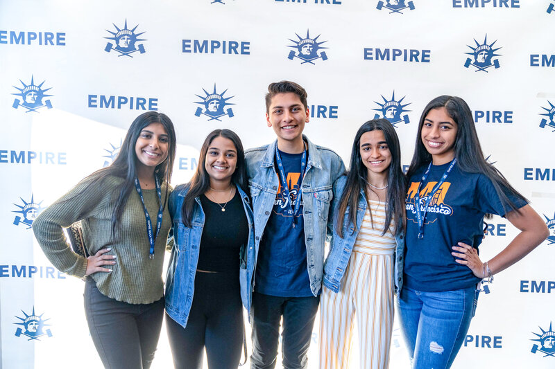 Students in front of Empire branded backdrop