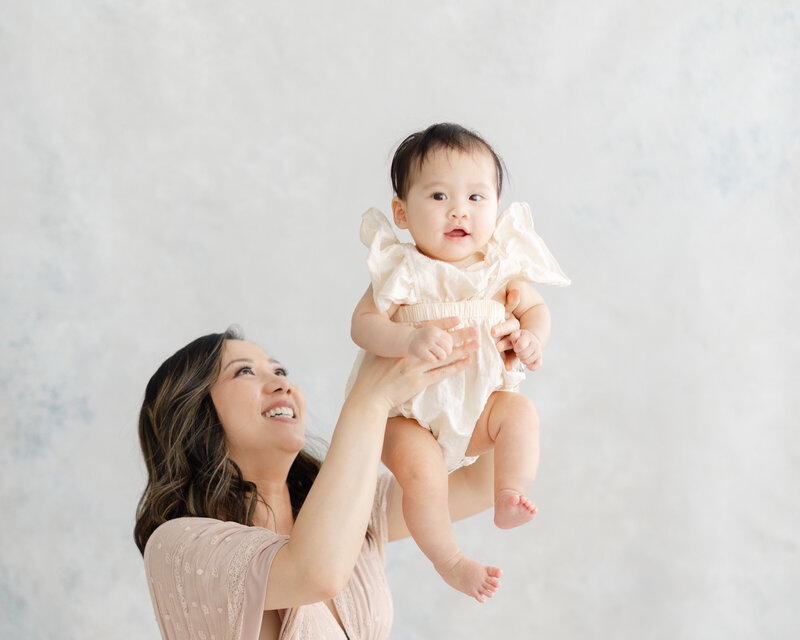Mother holds young baby up in the air