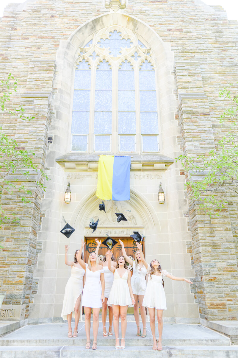 Loyola grads toss their caps outside of the Loyola Maryland chapel during their graduation session in Baltimore, MD