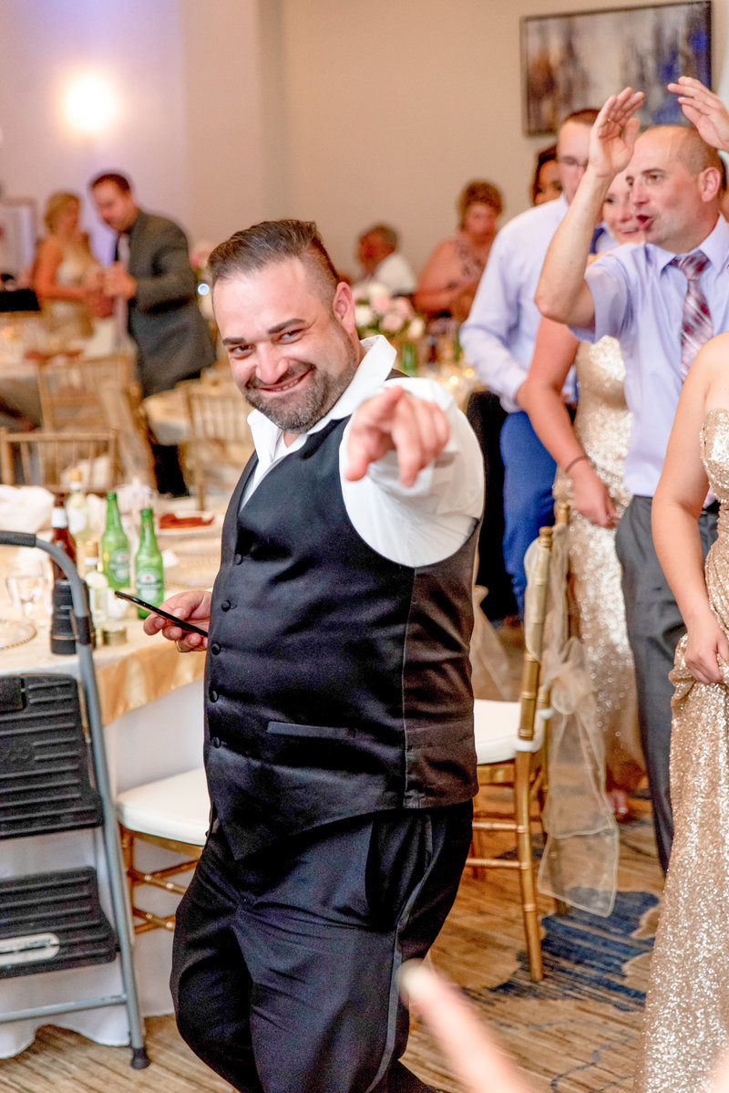 A wedding attendance acknowledges the camera by pointing