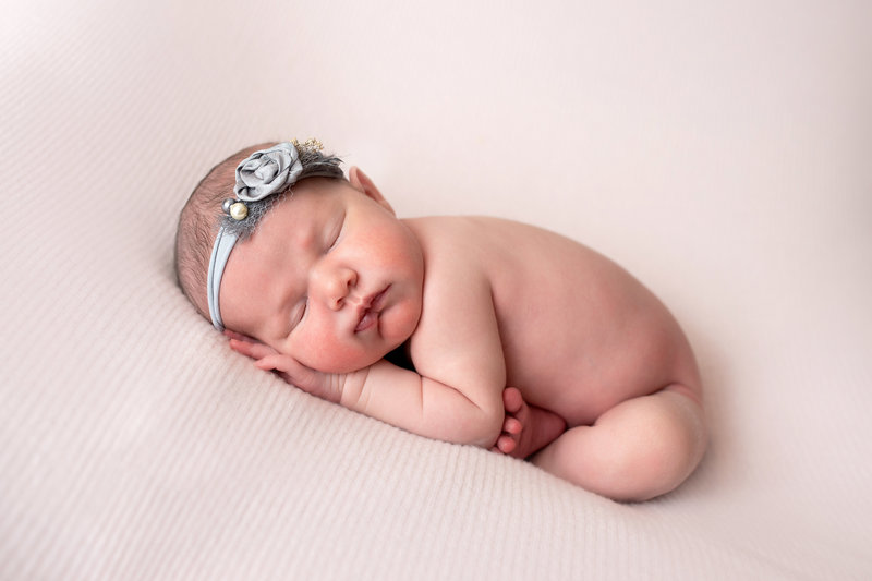 Newborn baby girl sleeping in tacco pose during Toms River newborn photo session.