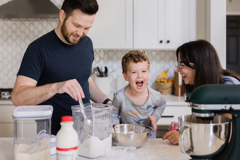 Mom and Dad mixing muffin batter in the kitchen with their laughing son