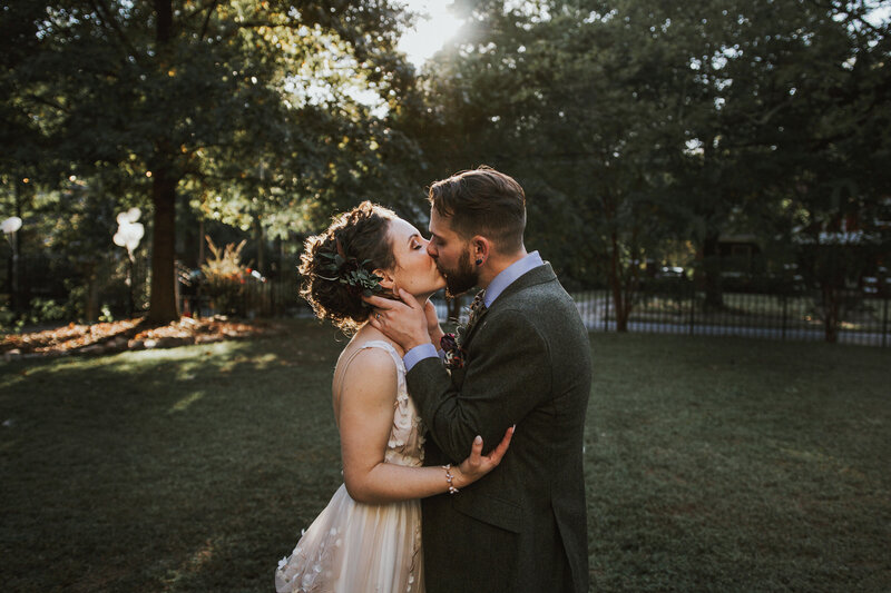 bride and groom kissing on a grassy lawn