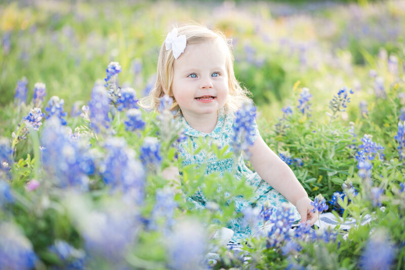 Girl with white bow sitting in bluebonnets, Austin Family Photographer
