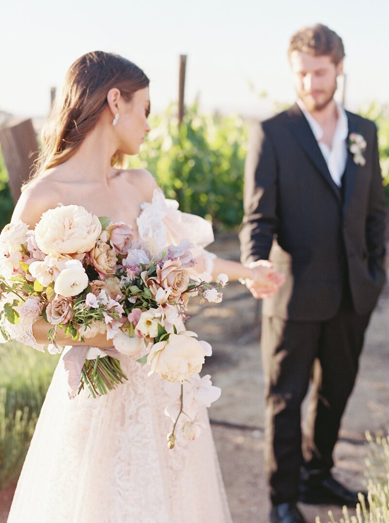 bride holding the grooms hand in a field of lavender
