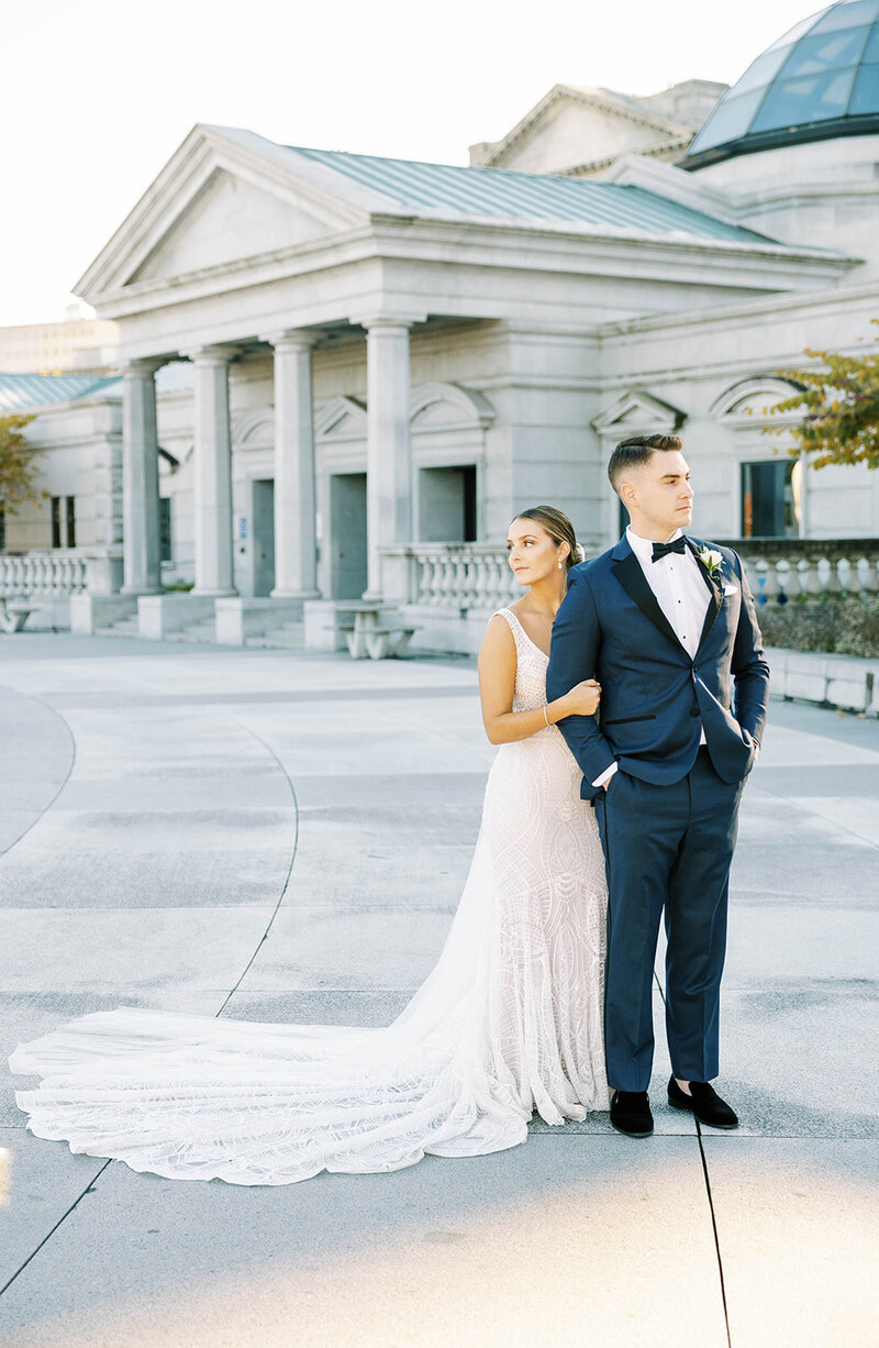 Bride holds groom's arm and poses next to backdrop of the PA State Capitol in Harrisburg.