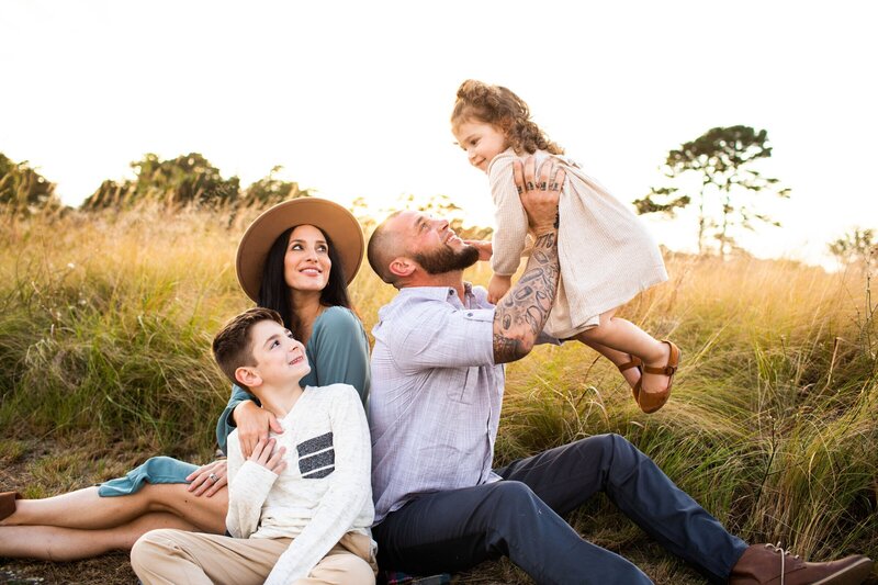 Family smiling and sitting in field by family photographers new jersey

