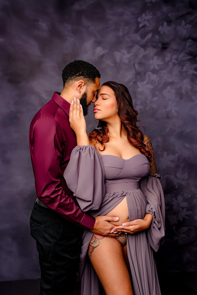 Expecting couple Embraces each other touching mom's belly nose to nose and a close intimate pose
