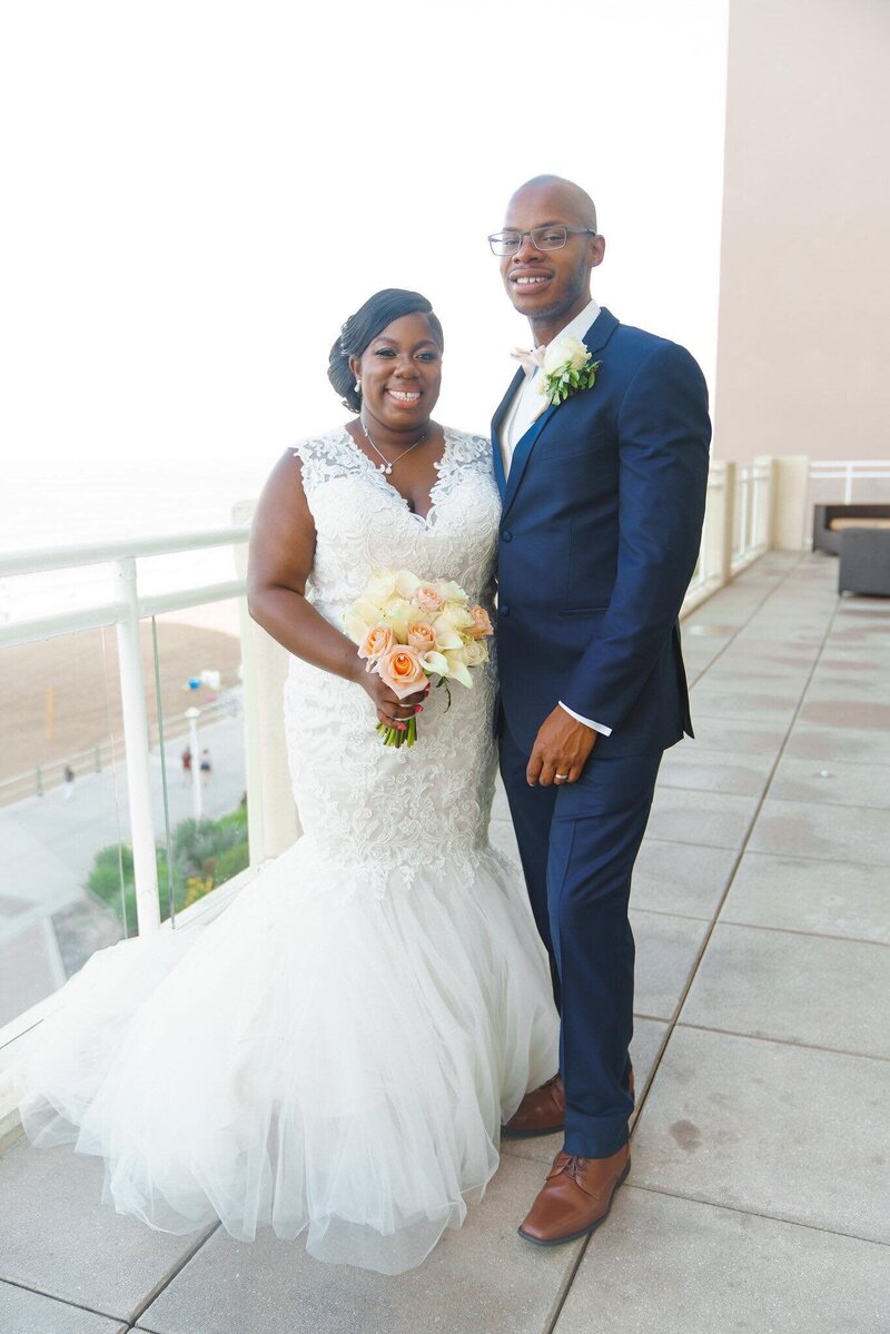 bride and groom pose on balcony at oceanfront wedding wedding dj