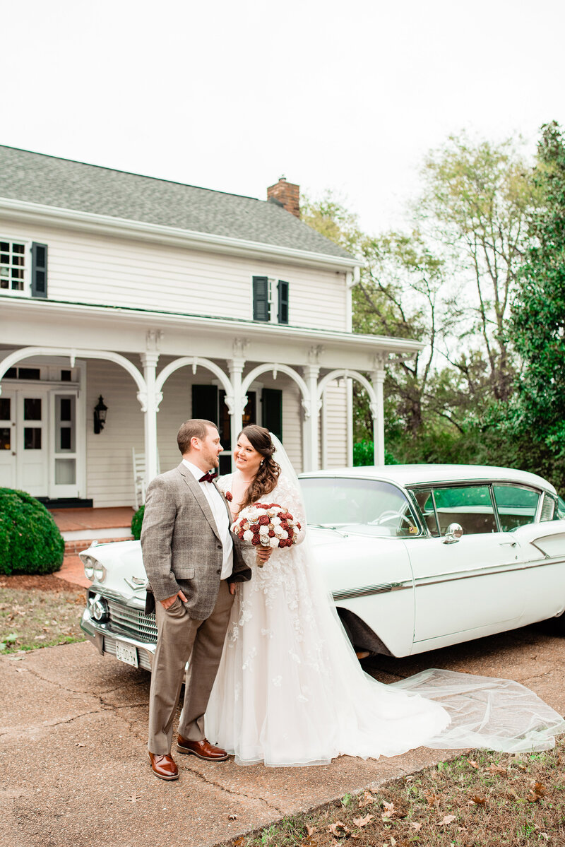 Newlyweds standing by a vintage car in front of the Cool Springs House
