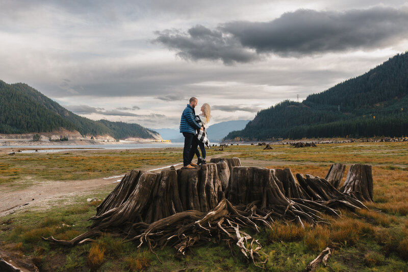 Engagement session in the Snoqualmie Pass area. Couple standing on a tree stump.
