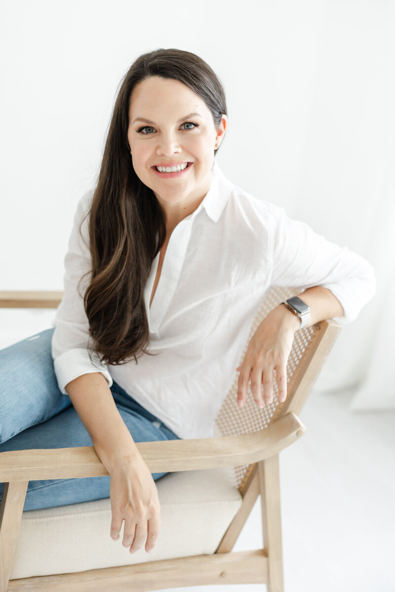 Connecticut newborn and family photographer, Kristin Wood, smiles for portrait in white blouse and jeans