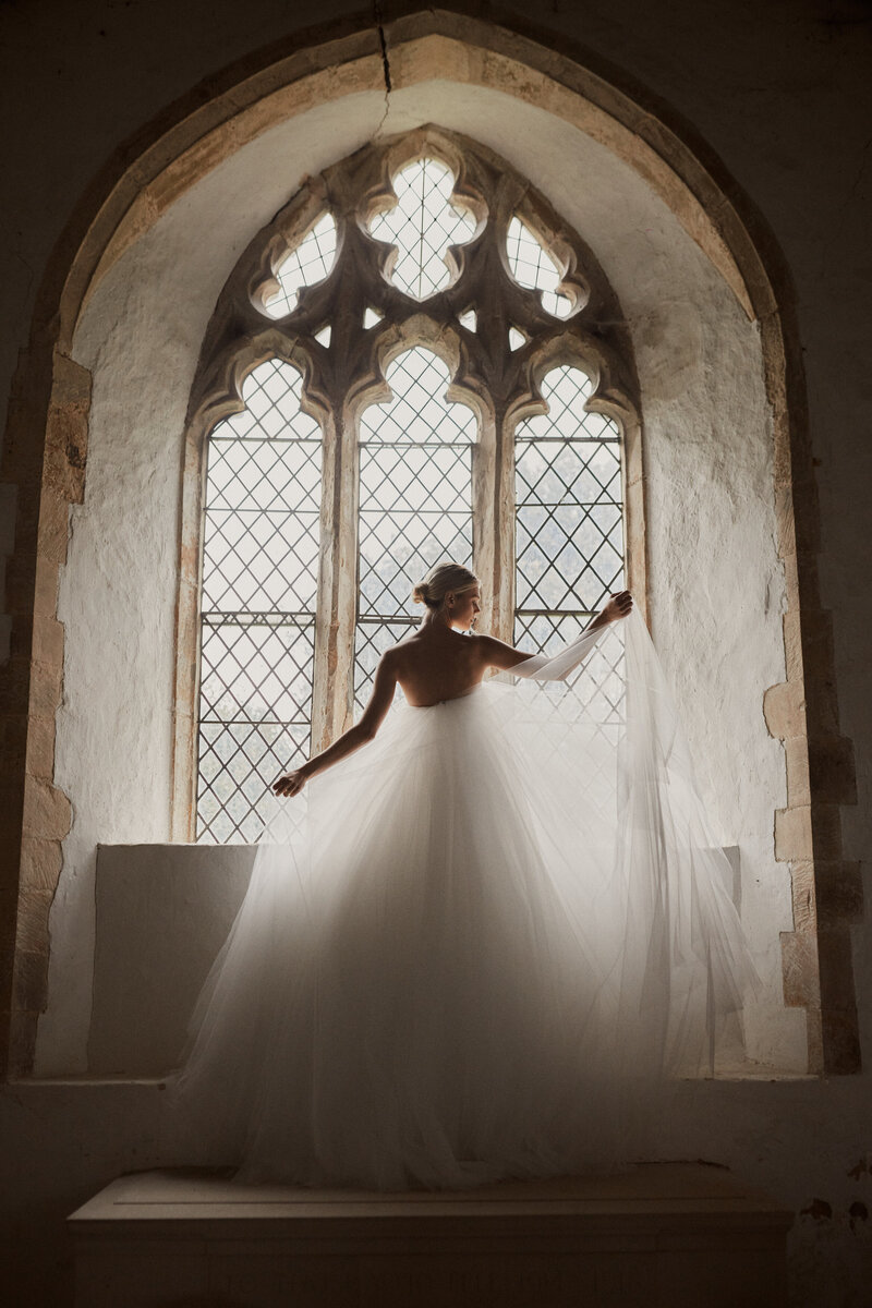 Backless modern wedding dress on bride in church window, Vanity Fair photo