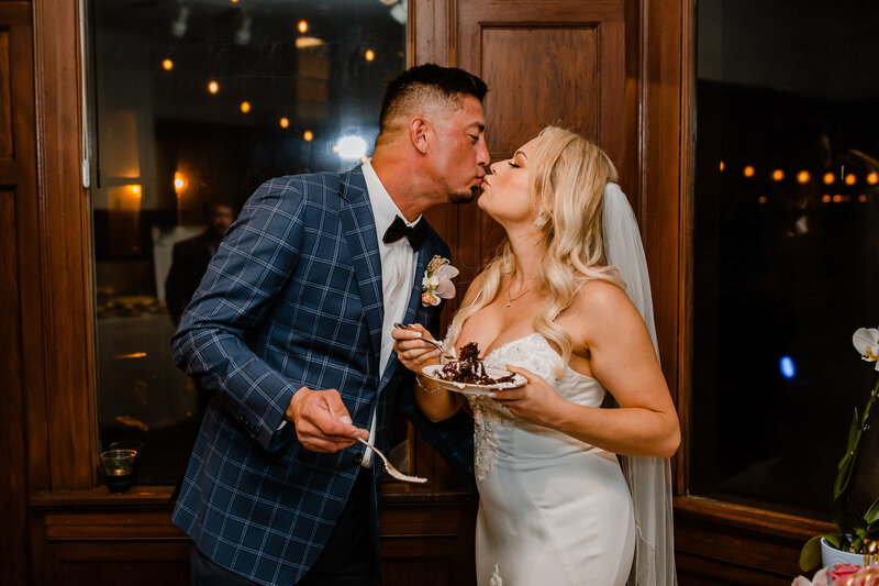 bride and groom share a kiss while eating cake