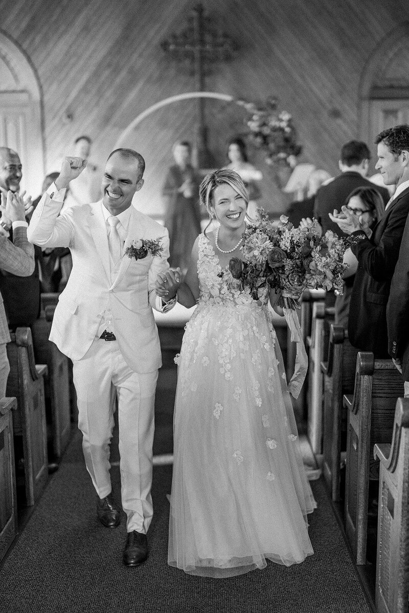 Bride and groom beam with joy walking up the aisle after their ceremony at a California chapel, captured by a film wedding photographer.