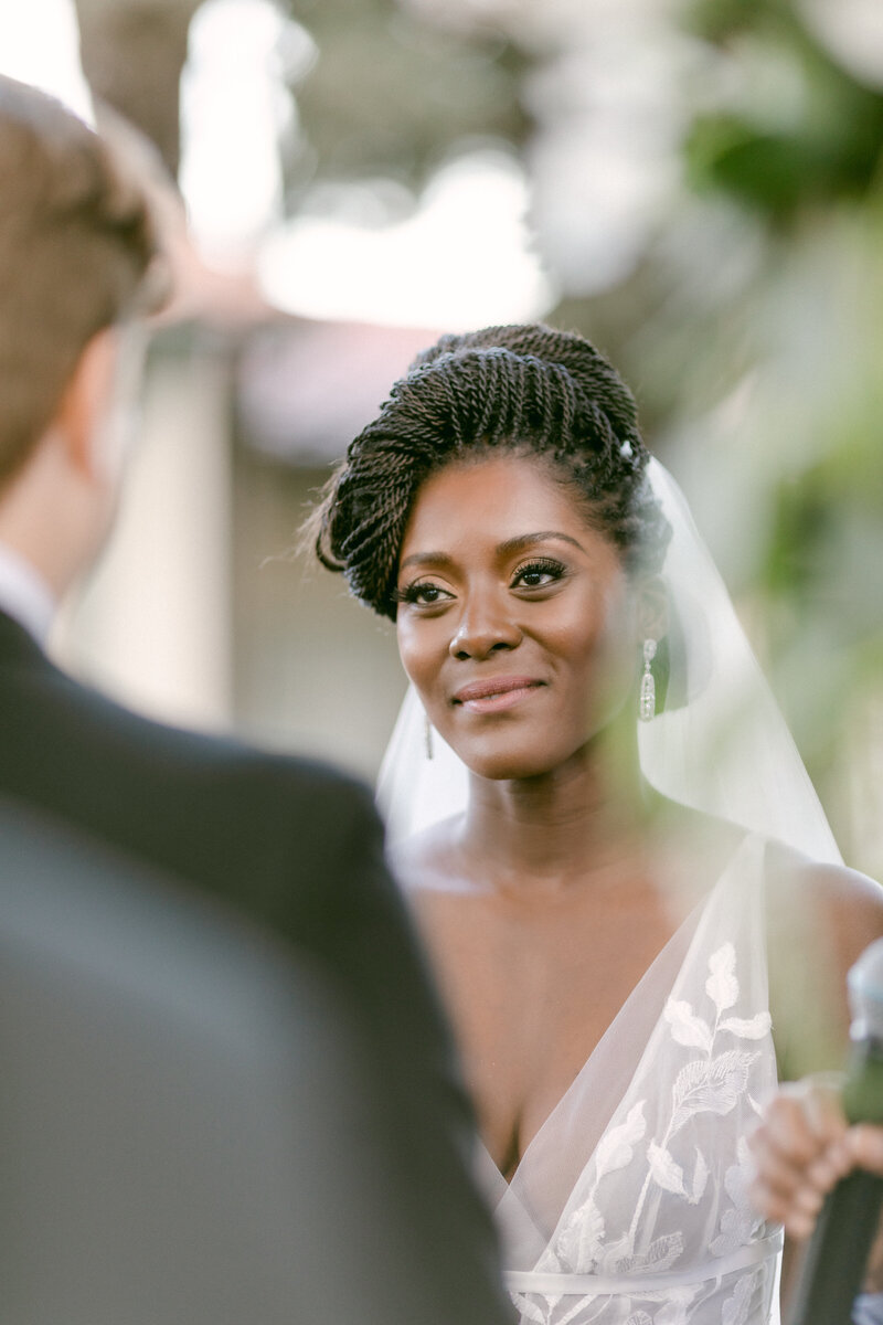 Stunning African American bride smiles at her husband-to-be as she takes her vows