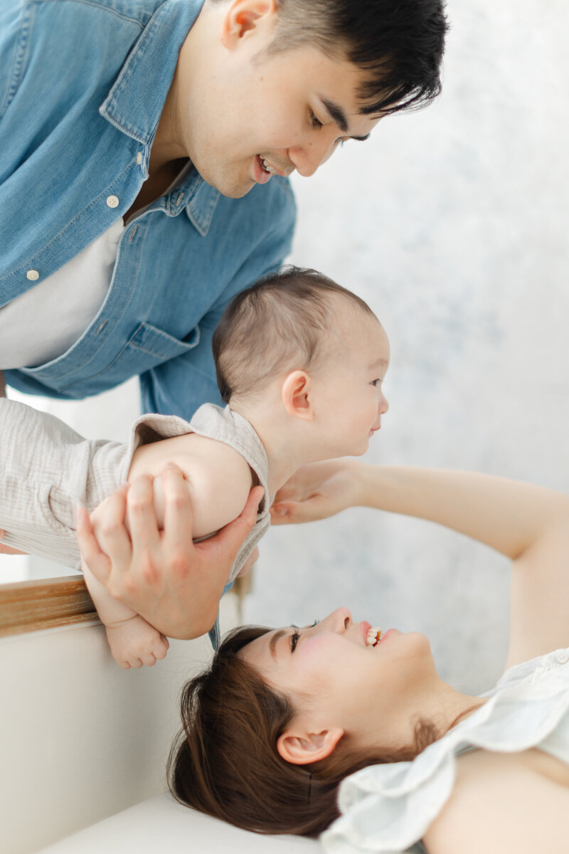 Dad holds his young baby over mother