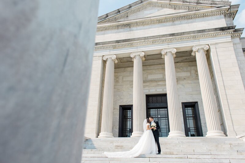 A bride and groom kissing on the steps in front of the Cleveland Museum of Art