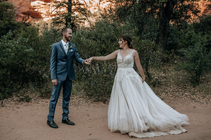 bride in full skirt tulle wedding dress with sparkly sequin top and groom in blue grey suit in sedona canyon wedding