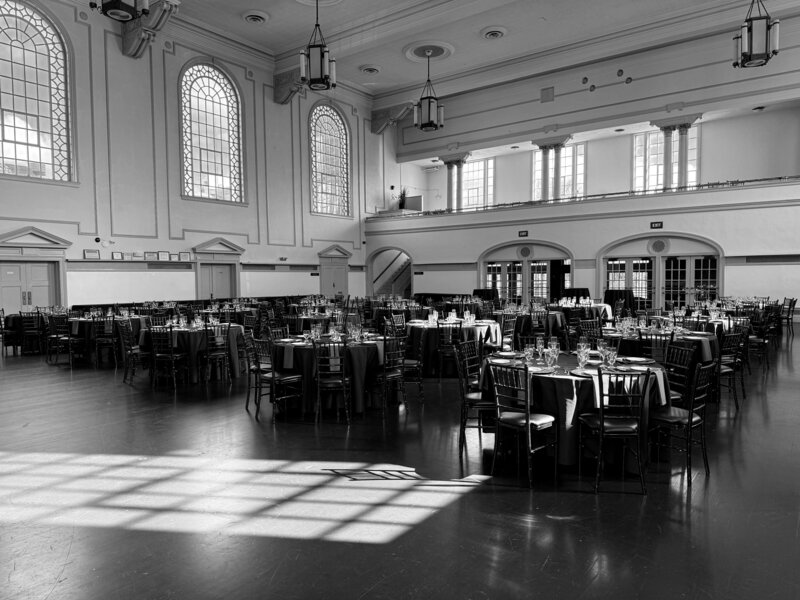 Black and white photograph of empty vintage hall with chandeliers and rows of chairs – photographed by wedding photographer Niko Coric – Lumen Clarity Media