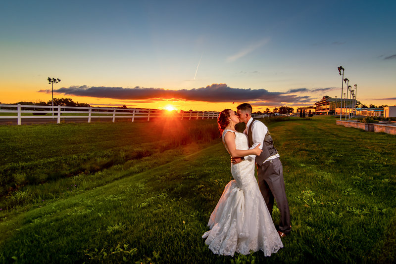 Vibrant sunset at Vernon Downs Racetrack with Bride and groom kissing