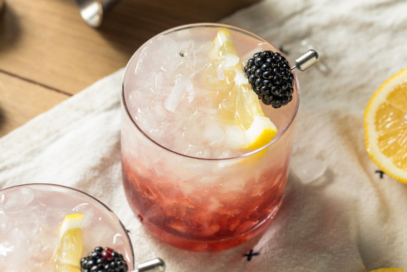 Cocktail garnished with blackberry & lemon