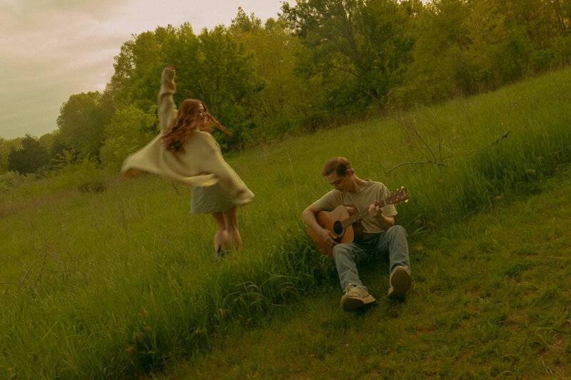 A recently eloped couple holds hands and runs through the woods together in dreamy, summer lighting
