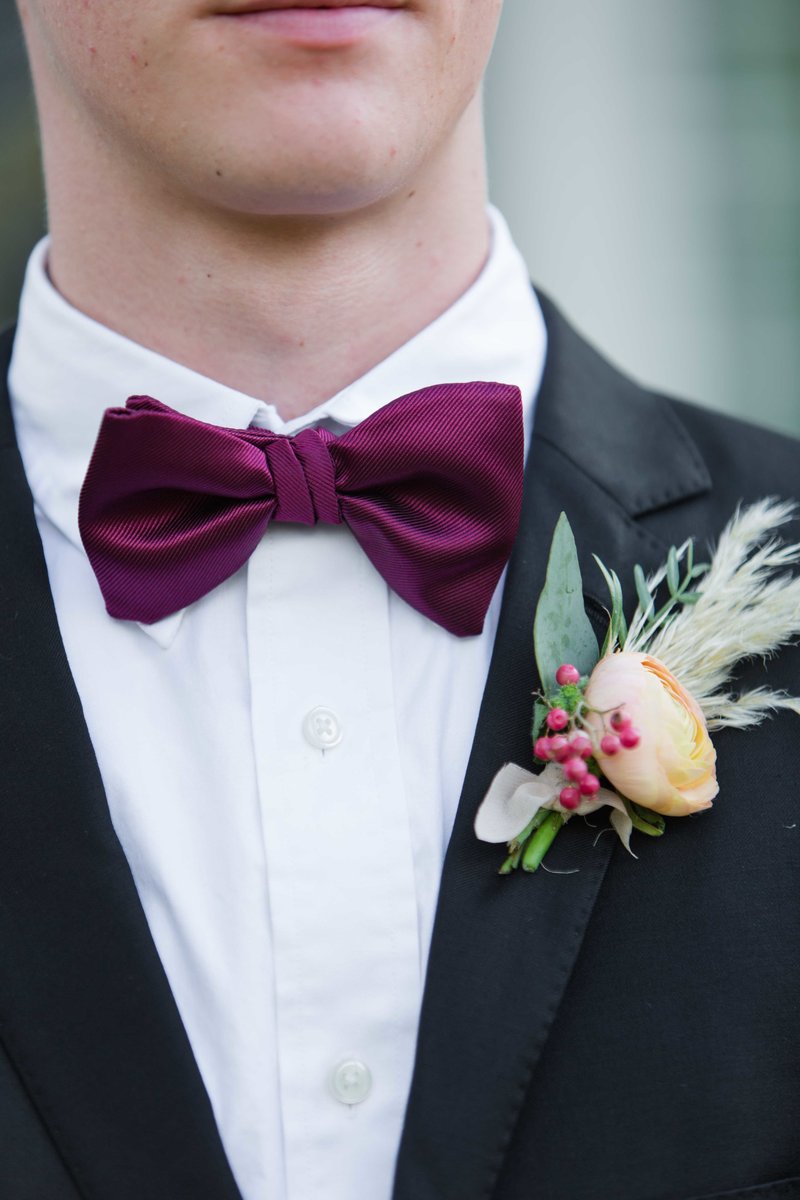 Groom wearing a burgundy bowtie with boutonniere.