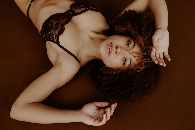 african american woman laying on the ground in black lingerie