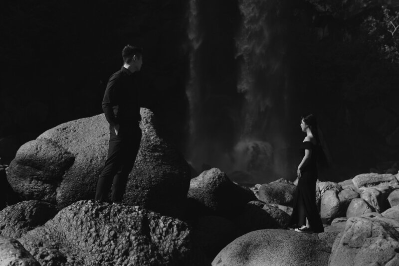 a couple dressed in black look at Jeongbang Waterfall in Jeju