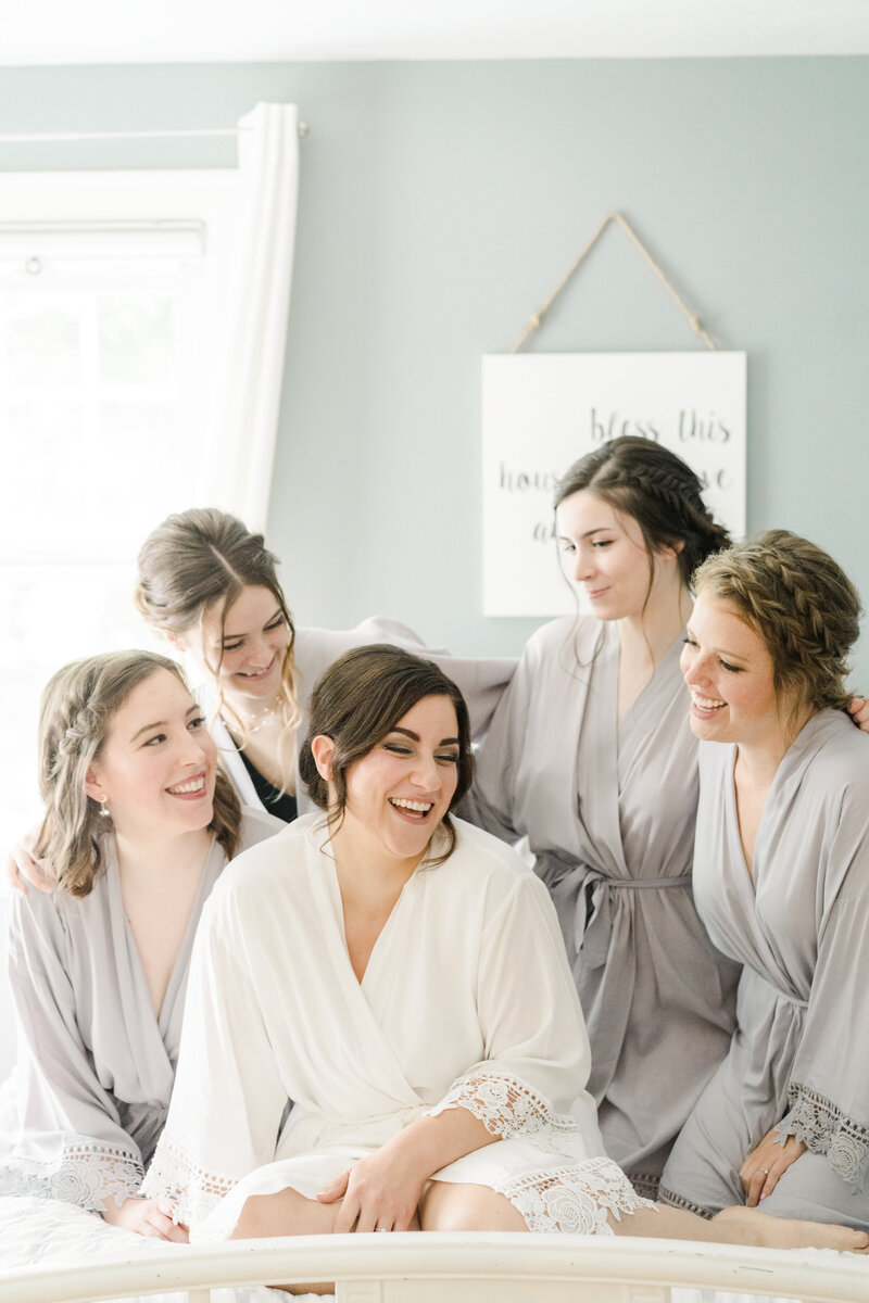 bride and bridesmaids on bed looking at each other and laughing
