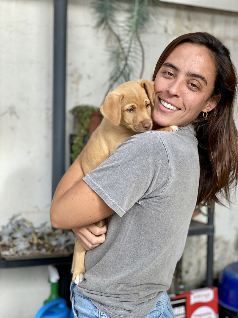 woman in gray shirt holding a puppy