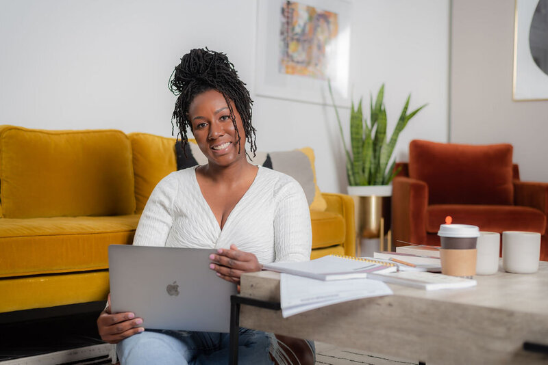 maryland accountant smiling with a grey macbook in her lap and papers on her coffee table