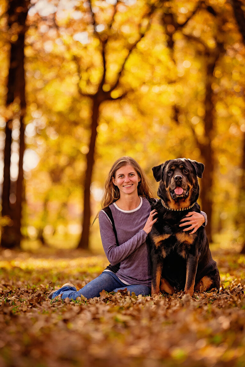 Fall pet portrait of woman sitting with her Rottweiler.