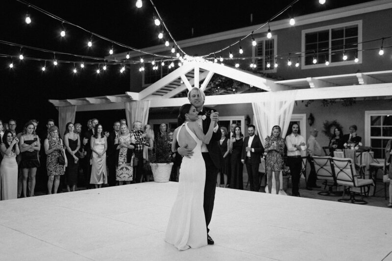 13-radiant-love-event-2021-outdoor-reception-bride-groom-dancing-guests-standing-around-white-dance-floor-black-white-romantic-elegant-timeless