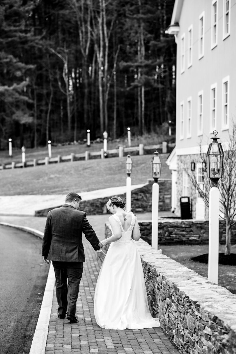 Black and white photo of a Couple walking together outside their wedding venue