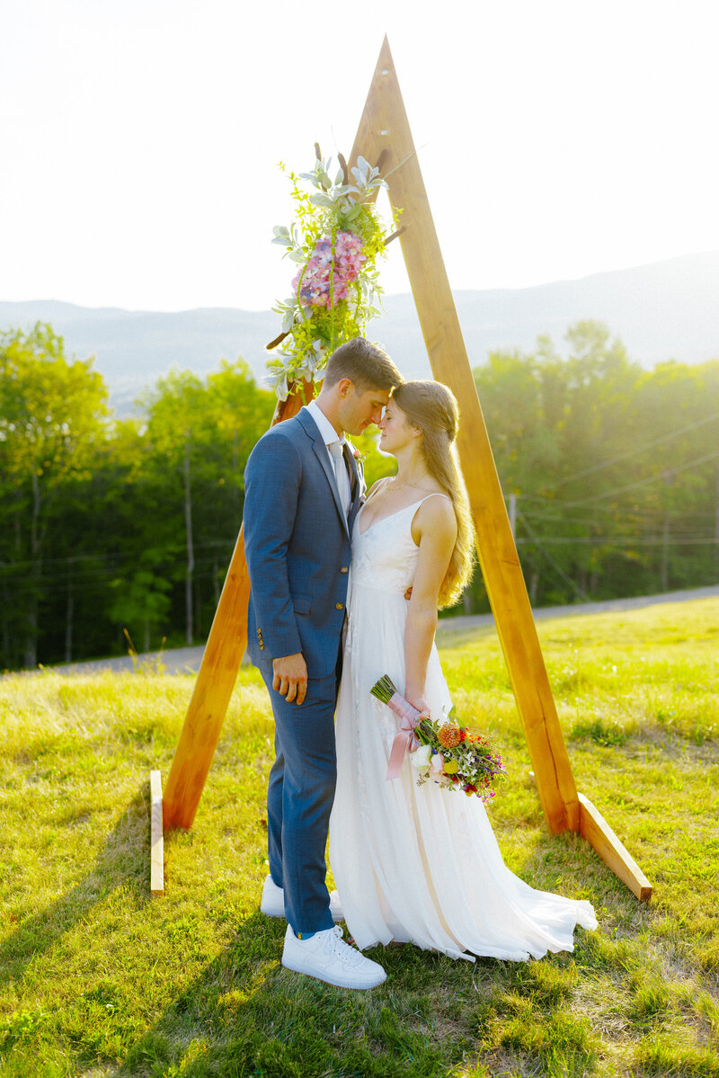 bride and groom portraits in front of ceremony arch in rumney new hampshire
