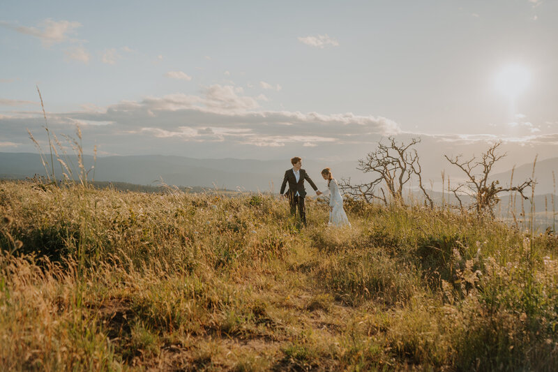 Bride and groom walking on a grassing mountain top