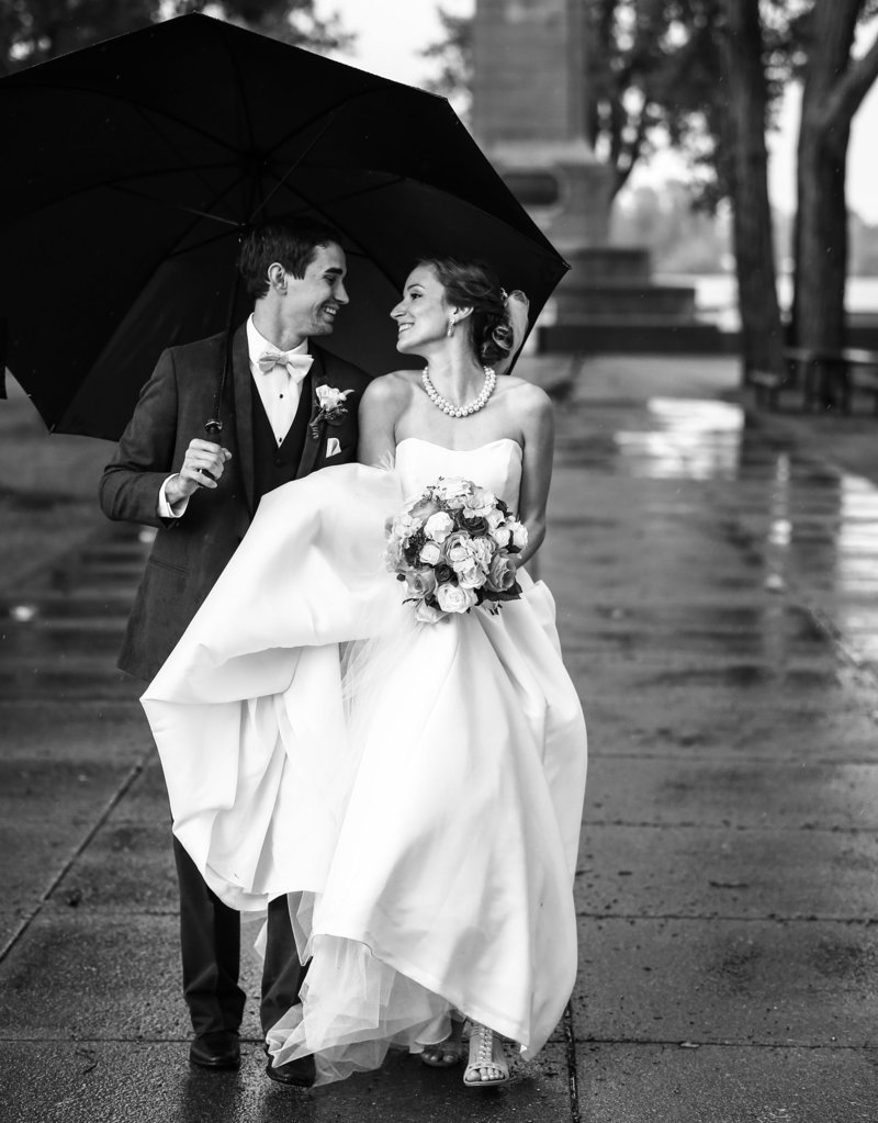 Bride and groom smiling under an umbrella in front of Perry Monument at Presque Isle State Park