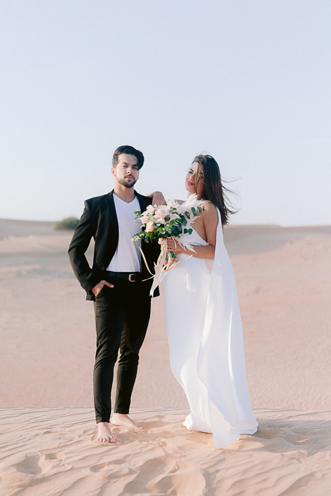 couple posing in front of the camera during a photoshoot in the desert of dubai