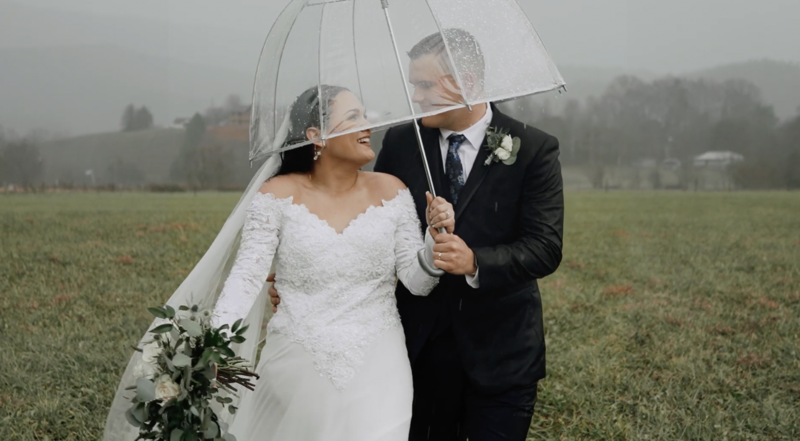 newlyweds walk under umbrella in rain
