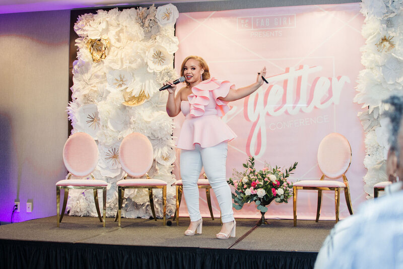 woman in a pink top and white pants speaking on a chicago conference stage