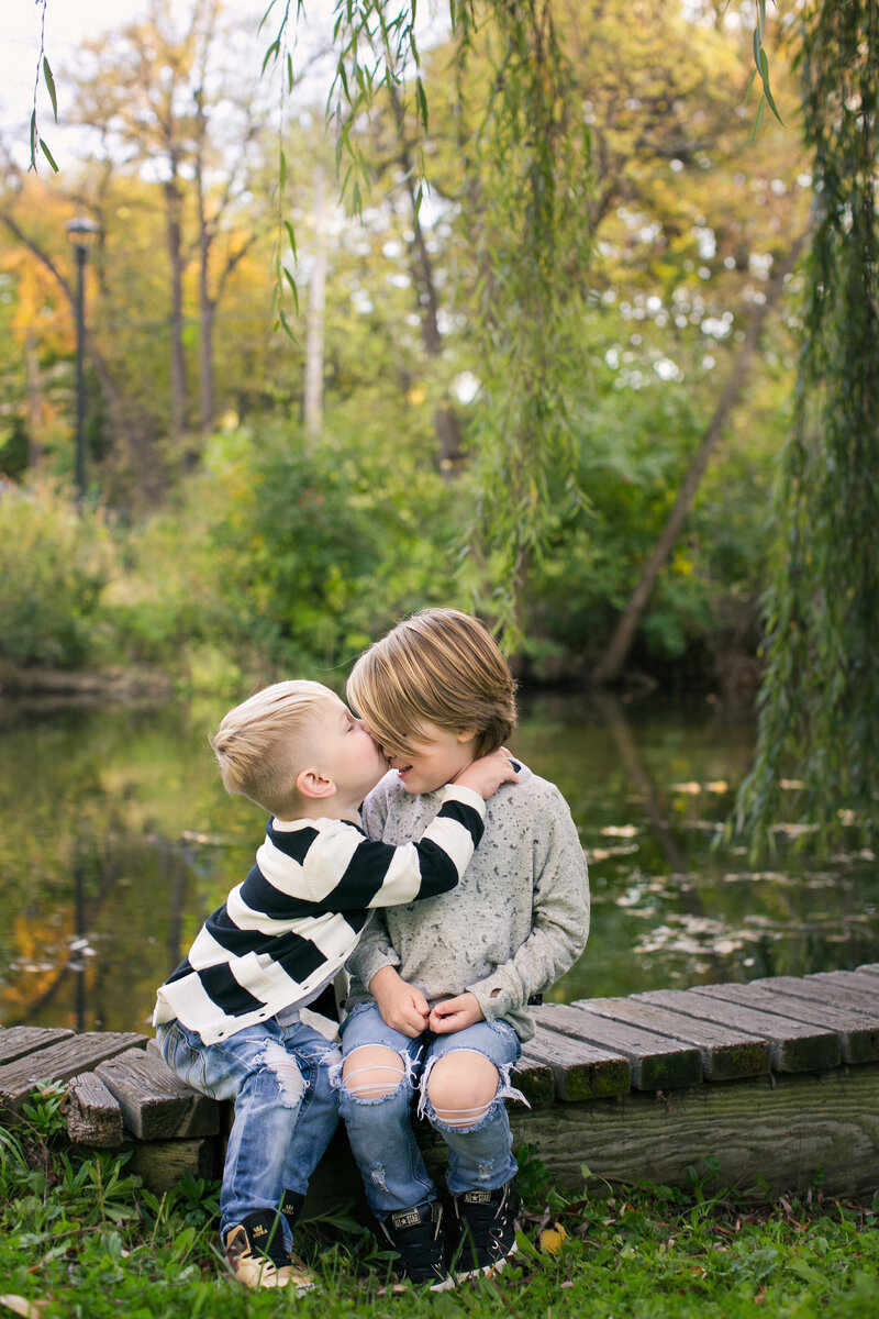 two boys hug on wooden bridge