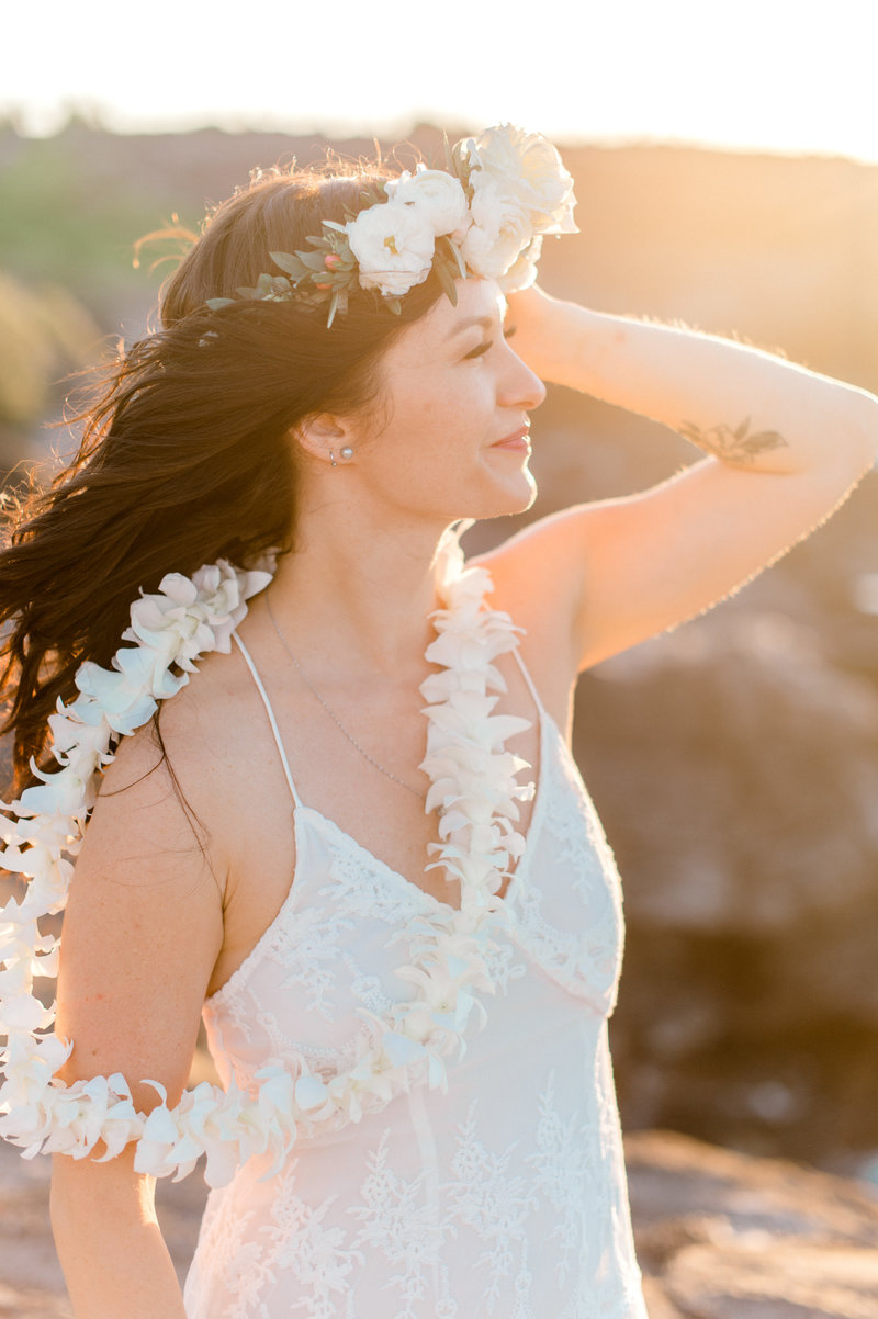 Bride wearing a white lei pohaku flower crown and white lei on her wedding day in Maui