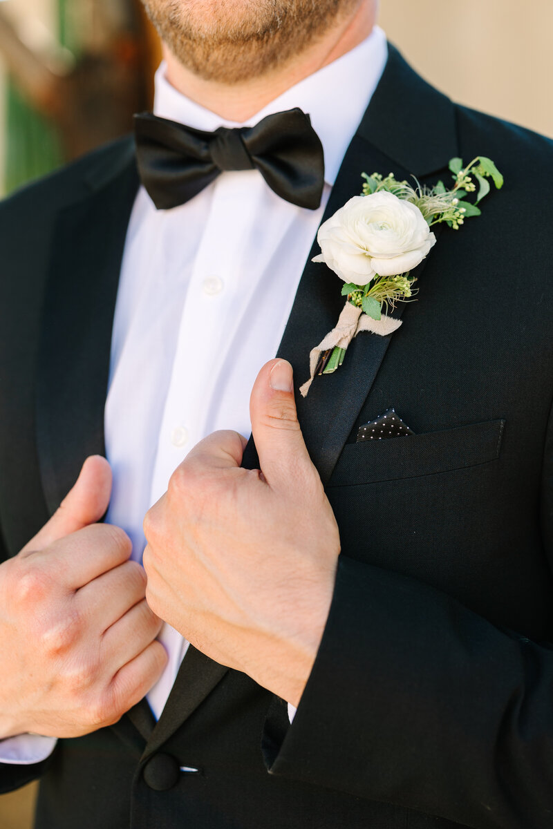 close shot of groom in tuxedo with white floral boutonniere.
