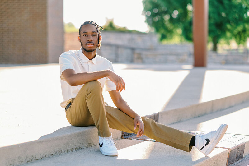 High school senior guy sitting on the steps of an outdoor amphitheater for his senior guy pictures