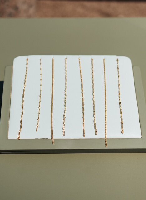 Multiple gold-filled chain styles shown on a jewelry display card, featuring fine and textured links.
