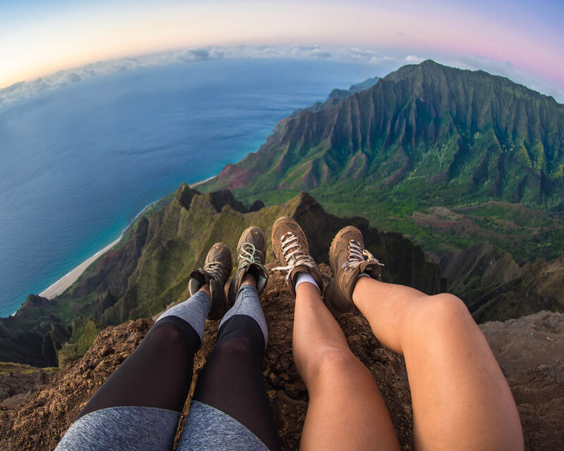 Micaela and her friend sitting on top of a mountain in Kauai, Hawaii