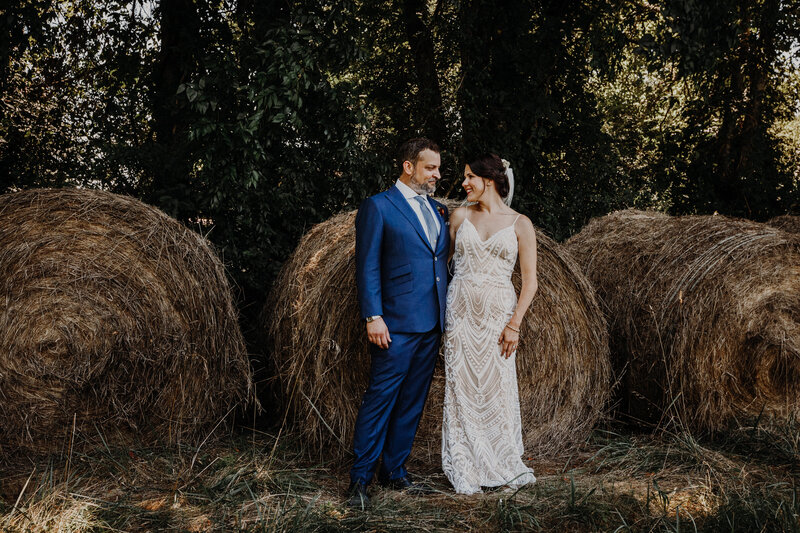 bride and groom in front of large hay bales
