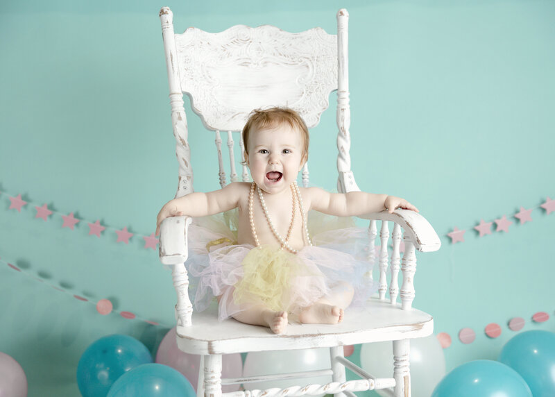 Baby on a chair with a teal background